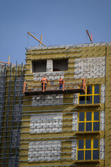 Workers sheathe the outer walls of the building with insulation.Insulation of the facade of the building.Exterior finish