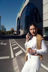 Fototapeta premium Latin businesswoman drinking coffee and holding clipboard at the city