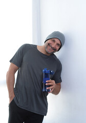 fifty year old man smiling and drinking water after a gym session