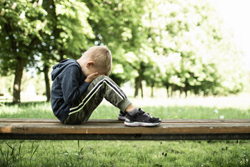 Sad lonely child crying on park bench 