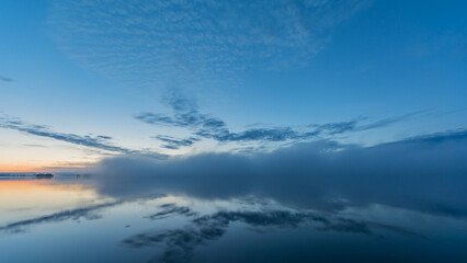 Fototapeta premium Summer lake scenery with clouds and mist reflected on the water in Finland