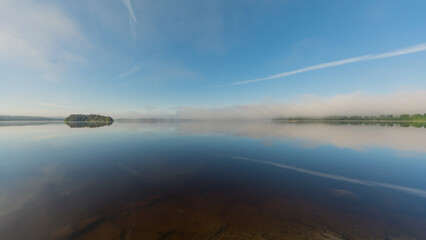 Summer lake scenery with clouds and mist reflected on the water in Finland