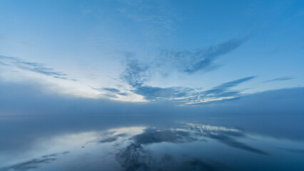 Summer lake scenery with clouds and mist reflected on the water in Finland