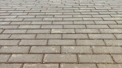 Background and texture of tiles on the sidewalk. The sidewalk on the street is made of pieces of tile or brick. Gray color outdoors.