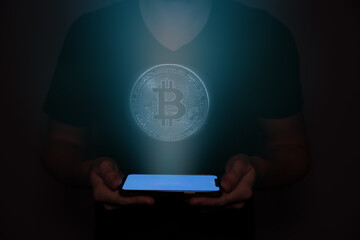 A bitcoin is projected from a cellphone held by a man. Futuristic technology with AI.