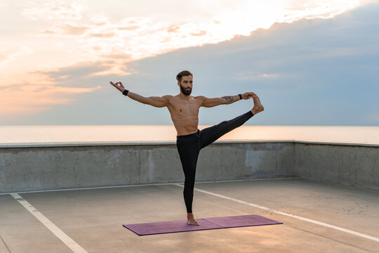 attractive hansome man with athletic strong body doing morning yoga asana outdoors