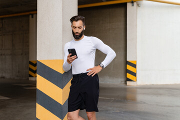 athletic strong hansome man on morning fitness workout exercise in sportswear using smartphone