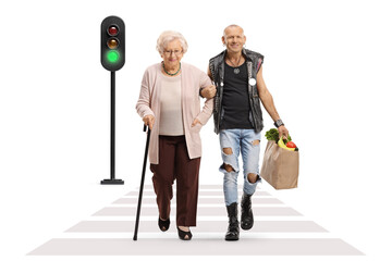 Man holding a senior woman under arm and carrying grocery bag at a pedestrian crossing