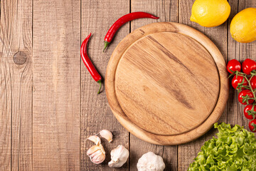 Wooden Cutting Board with Fresh Herbs and Raw Vegetables on Rustic Wood Table. Top view. Cooking background.