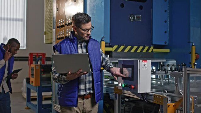 Close-up portrait of serious concerned hard-working Caucasian middle-aged male at workplace. Thoughtful handsome attractive man looks in his tablet and tap the electrician panel screen.