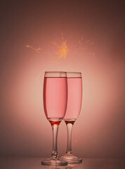 Pink champagne,wine isolated on a pink gradient background with some sparkles above the glasses.