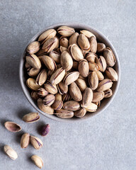 Bowl with pistachios on a grey concrete background. Green salted pistachios in a ceramic bowl. Copy space.