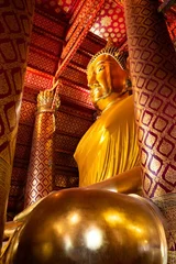 Papier Peint photo autocollant Monument historique Vertical low angle shot of a big golden Buddha statue in a temple in Ayutthaya, Thailand.