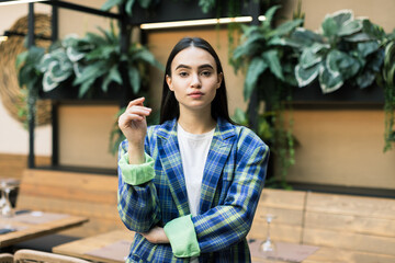Portrait of young beautiful woman looking at camera with crossed arms. Successful businesswoman restaurant manager standing at hall in modern style restaurant.