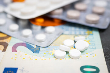 White round pills, blister packs with tablets, antibiotic, painkiller or drugs and money, Euro currency banknotes, expensive medicine and healthcare concept, close-up view