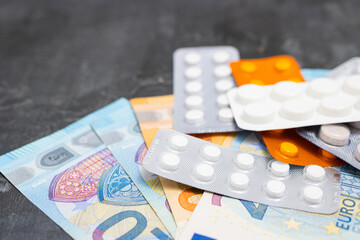 Blister packs with tablets or pills, antibiotic, painkiller or drugs and money, Euro currency banknotes, expensive medicine and healthcare concept, close-up view