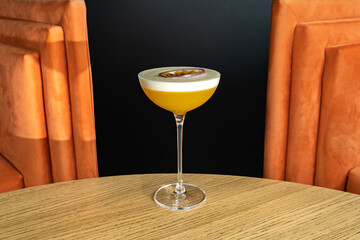 Summer cocktail garnished with passion fruit. rich yellow cold beverage on bar terrace.
