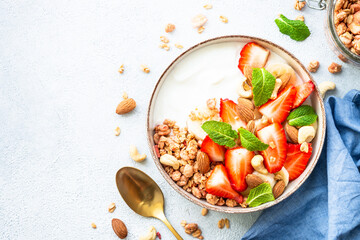 Yogurt with granola, nuts and strawberries on white. Healthy snack or breakfast, fruit salad. Top view with copy space.