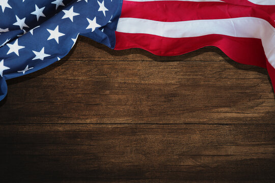 The American flag of the USA on a dark brown wooden table with enough space to write on it.