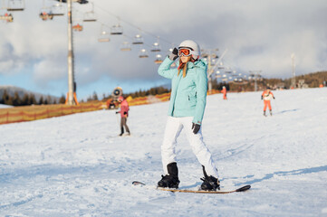 A beautiful girl snowboarder stands on a slope and prepares to descend