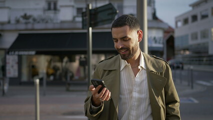 A Moroccan young man standing in street checking phone. One Middle Eastern male person looking content online with smartphone