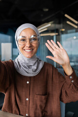 Close-up photo. Vertical photo. A young female blogger in a hijab talks to the camera, holds a...