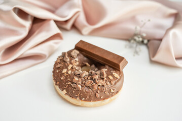 Fresh sweet chocolate Donut with splashes, on a white background, with a silk cloth