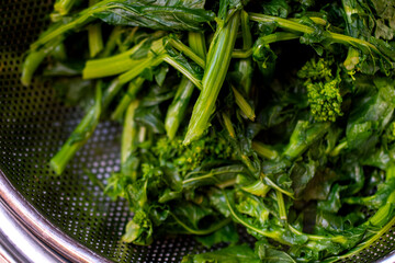 close up of steamed broccoli rabe in a food stainer  