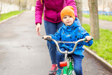 Obraz premium Young mom teaching son to ride bike first time in park