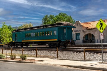 Green train cabin parked in front of the train station in Santa Fe and a road sign