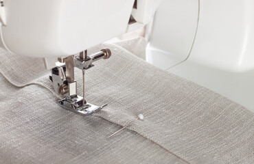 Modern sewing machine presser foot with linen fabric and thread, closeup. Sewing process clothes,...