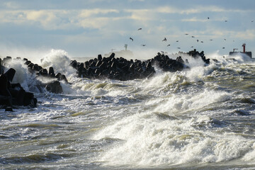 Coastal storm in the Baltic Sea, big waves crash against the harbor breakwater, breaking wave