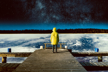 Surrealistic collage. A person stands on a bridge flying above the Earth, looks at the stars and space.