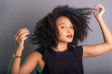 Portrait of beautiful young brunette woman messing with her hair. Dressed in black.
