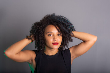 Portrait of beautiful young brunette woman messing with her hair. Dressed in black.