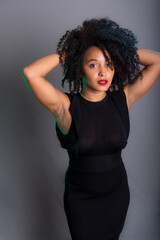 Portrait of beautiful young brunette woman messing with her hair. Dressed in black.
