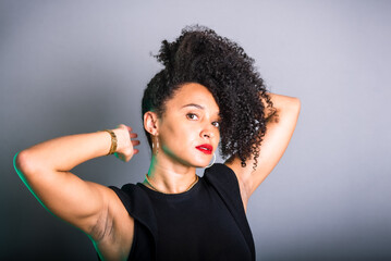 Portrait of beautiful young brunette woman messing with her hair. Dressed in black.