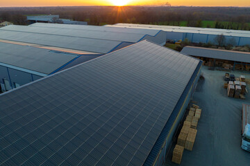 Aerial view of solar power plant with blue photovoltaic panels mounted on industrial building roof...
