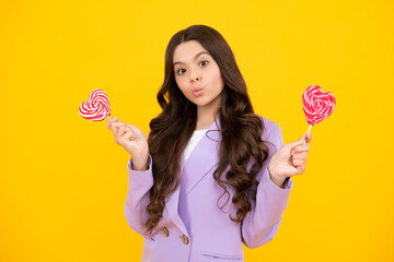 Funny face. Cool teen child with lollipop over yellow isolated background. Sweet childhood life. Teen girl with yummy lollipop candy.