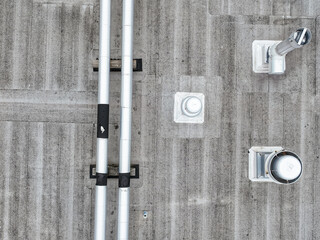 Aerial view of an Industrial looking HVAC equipment and pipes on gray roof.
