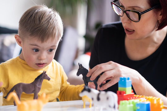  child with Down syndrome exploring their creativity and learning with colorful geometric shapes, supported by their family in a relaxed and enjoyable activity at home