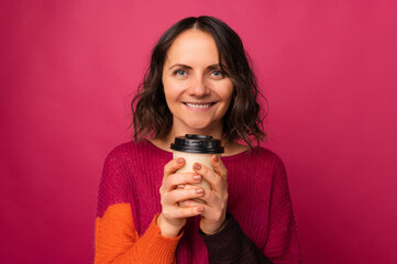 Close up studio portrait of a mid age woman holding a to go cup of coffee.