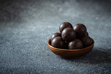 Obraz premium Small wooden plate with chocolate balls on dark blue background 