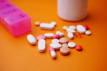  colorful pills and capsules on orange color background 
