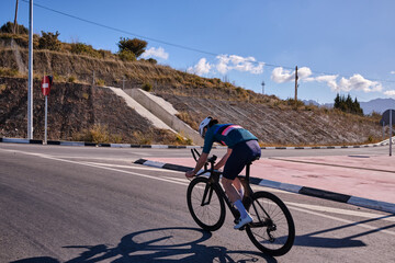 Male athlete riding time trial bicycle on empty road.Focused on Goals: Motivated Male Triathlete...