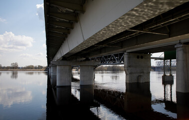 Reinforced concrete bridge across the river during the flood flood of the river. A large water level in the river under the bridge on supports.