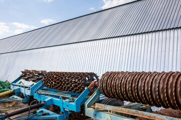 Old disc harrow for tillage are standing near the arches hangar on the material and technical base...