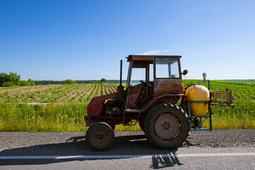 An old farm tractor with a sprayer and tank capacities is preparing to spray a crop protection...