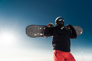 A strong male snowboarder extreme sport, mirrored glasses in a white helmet and ski suit stands on...