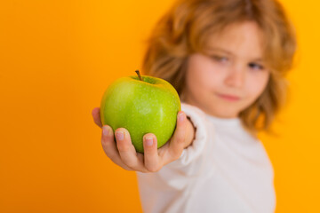 Healthy fruits for kids. Kid with apple in studio. Studio portrait of cute child hold apple isolated on yellow background.